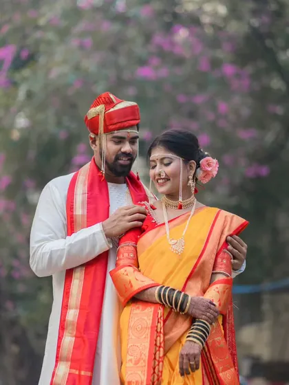A gentle moment between the newly married couple. The groom adjusts his bride's mundavalya, a small, intimate gesture that speaks volumes about their new life together.