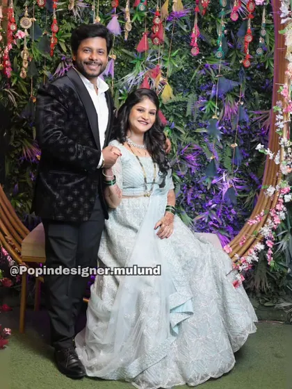 A beautiful shot of the couple seated, showcasing the intricate embroidery of her gown and the sharp tailoring of his tuxedo.