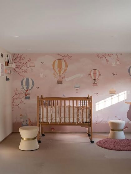 This enchanting children's room features a captivating wallpaper with colorful hot air balloons. A cozy wooden cradle is nestled in the center, creating a comfortable and wondrous haven for a little one.