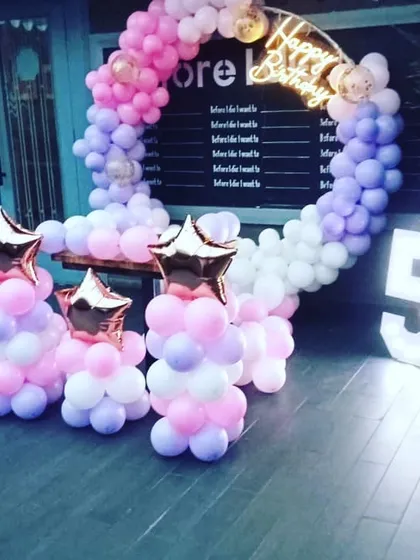 A pastel-colored balloon ring for a 5th birthday. This setup includes star-shaped foil balloon columns and a large light-up number '5', perfect for an outdoor or cafe party.