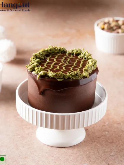 Indulge in our Mango Pistachio Dubai Kunafa Bento Cake. It features layers of chocolate sponge, pistachio cream, Alphonso mango, and crunchy kunafa, all wrapped in a glossy chocolate glaze.