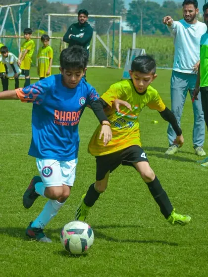 Two players from opposing teams are in a close tackle, both focused on winning possession of the ball.