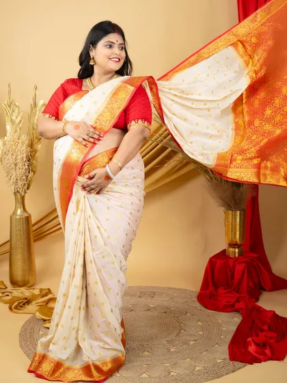 A joyful portrait of a mom-to-be in a beautiful white and red silk saree. The flowing fabric and her happy expression create a dynamic and celebratory image.