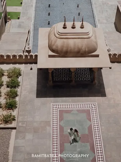 An aerial drone shot capturing the grand scale of the Fairmont Jaipur courtyard as the couple shares an intimate moment.