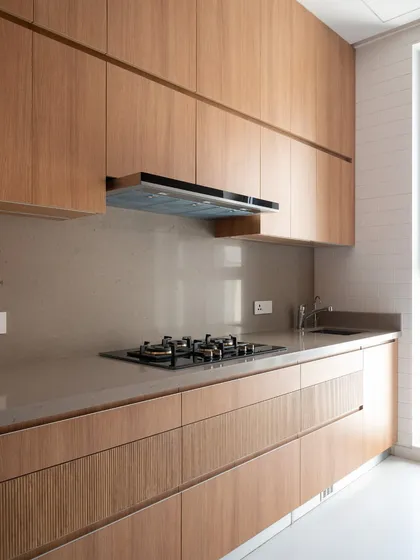 This kitchen showcases the beauty of minimalism, with handleless fluted wood cabinets and a neutral quartz countertop. The design is clean and uncluttered, creating a sense of calm and order.