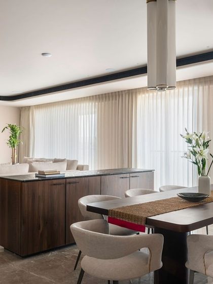 This view shows the seamless flow between the living and dining areas in the Parishram residence. A custom wooden credenza acts as a subtle divider while providing ample storage, maintaining the open and airy feel of the space.