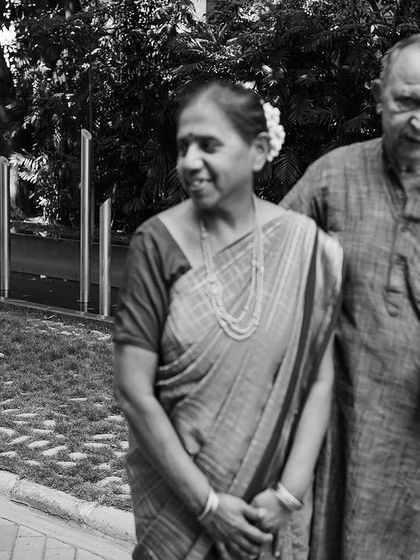 A classic black and white portrait of grandparents, made even more special by the joyful photobomb from their grandchild in the background. It's a perfect, unscripted family moment.