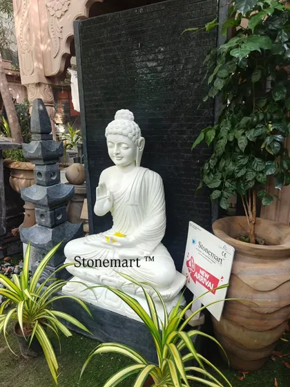 The Blessing Buddha fountain shown with surrounding greenery and a Japanese-style stone lantern. This demonstrates how our fountains can be integrated into a complete landscape design for a zen garden feel.