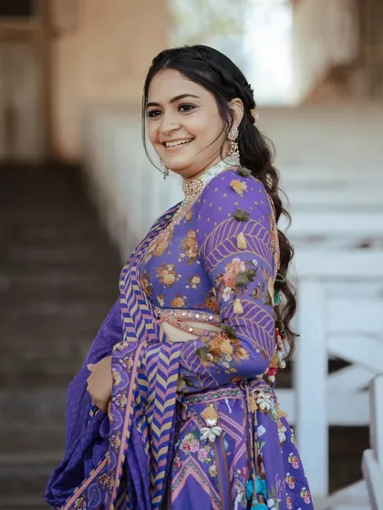 A smiling client showing off her gorgeous floral braid and wavy hair.