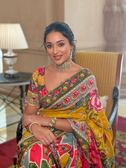 A seated portrait that showcases the intricate details of the floral saree and the client's relaxed elegance.