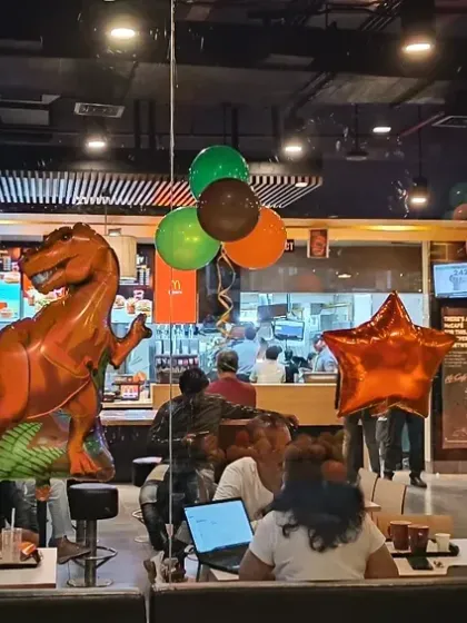 Dinosaur-themed foil balloons and balloon clusters set up in a restaurant party area.