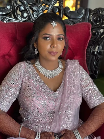 A classic portrait of Surya seated in a regal red chair. Her makeup is soft and glamorous, and her expression is serene and confident.