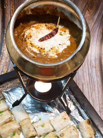Our Dal Makhani fondue, kept warm over a candle-lit stand. It's served with mini naan rolls, making it a perfect centerpiece for a table.