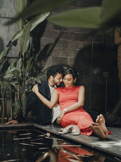 An intimate pre-wedding photo by the water's edge at dusk. The soft lighting and serene setting create a deeply romantic and cinematic feel.