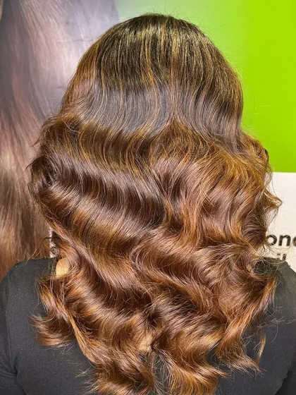 The stunning "after" result. We added rich caramel highlights and styled her hair in soft waves to show off the new color.