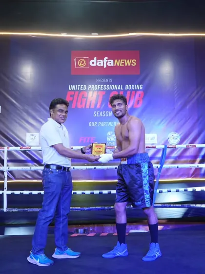 A boxer receiving his winner's plaque at the UPB Fight Club Season Finale. Consistent performance leads to recognition.