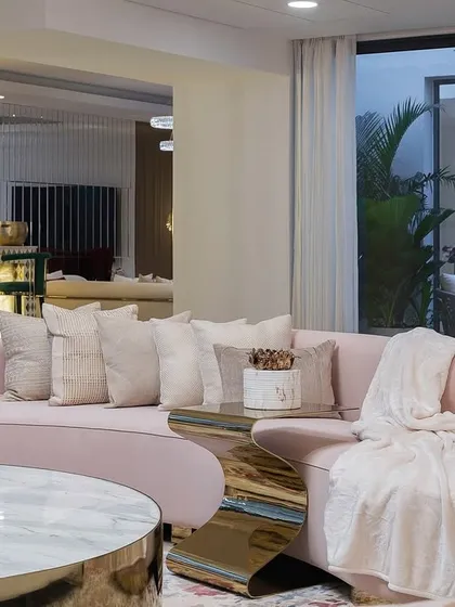 A close-up of the custom blush pink sofa, showcasing its gentle curve and plush fabric. This piece was designed to be the heart of the living room, inviting family and friends to gather and relax.