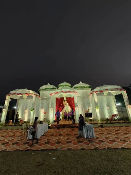 A straight-on shot of the completed dome-style wedding venue at night. The combination of white drapes, red accents, and warm lighting creates a classic and welcoming look for guests.