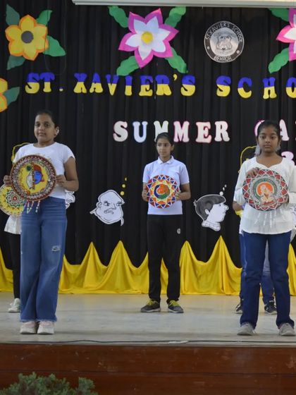 Students on stage at the summer camp closing ceremony, showcasing the beautiful mandala-style art they created during the workshop.