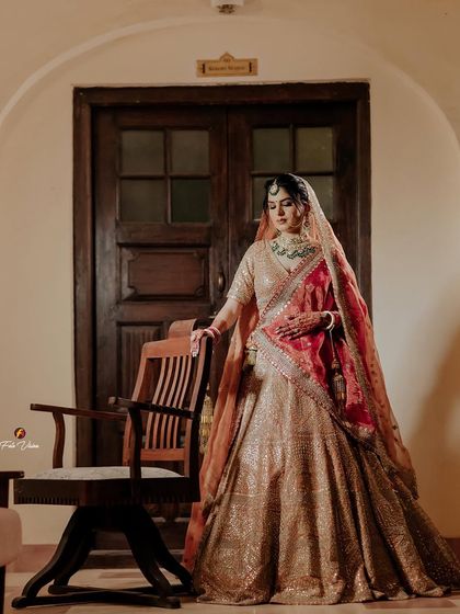 A poised and elegant portrait of the bride standing in a heritage room, her outfit complementing the classic, rustic interior.