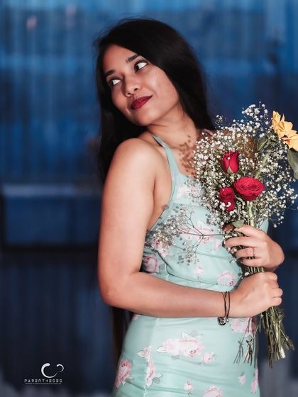 A joyful and confident portrait with a beautiful smile. The flowers add a touch of romance and color to this lovely outdoor shot.