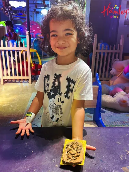 A smiling boy proudly displays the clay Ganpati he made. It's so rewarding to see the pride on their faces after they've created something with their own hands.