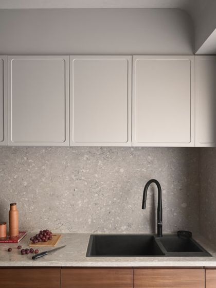 The kitchen countertop and backsplash are made from a durable and beautiful grey terrazzo. Paired with a modern black sink and faucet, the look is clean, timeless, and practical.