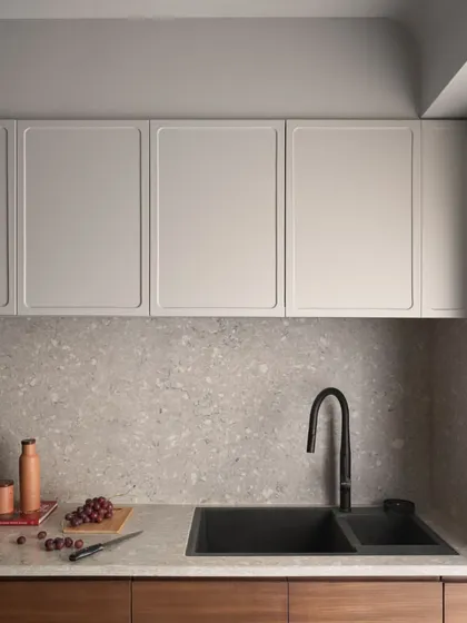 The kitchen countertop and backsplash are made from a durable and beautiful grey terrazzo. Paired with a modern black sink and faucet, the look is clean, timeless, and practical.
