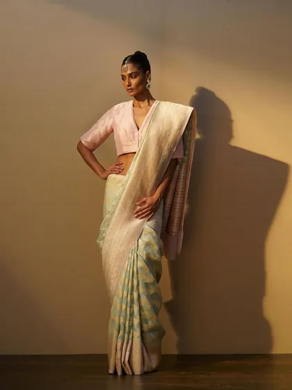 A full-length view of the pastel blue and cream saree, demonstrating its graceful drape and understated beauty.