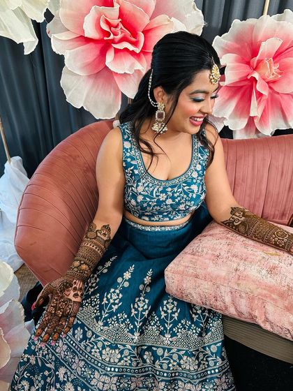 A happy bride showing off her full-arm portrait mehndi.