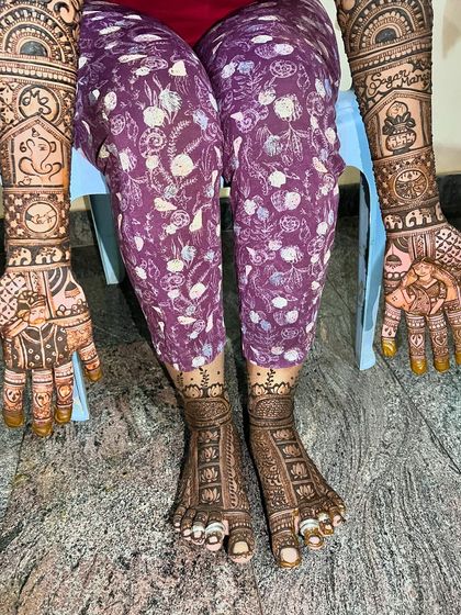 A complete bridal mehendi set. The hands feature detailed portraits and symbols, while the feet have complementary patterns, creating a beautiful, unified look.