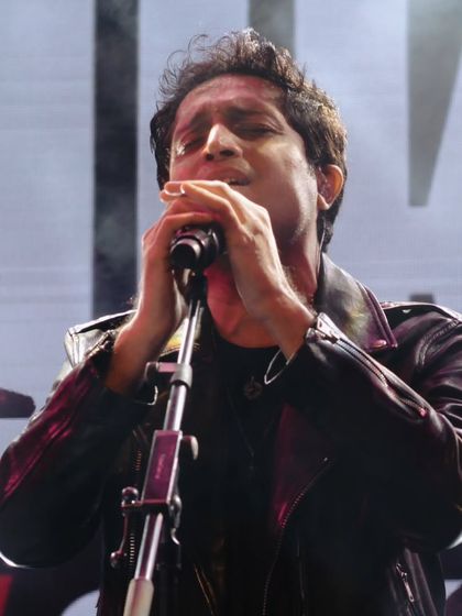Nikhil D'Souza playing the harmonica, demonstrating his multi-instrumental talent during his live sets.