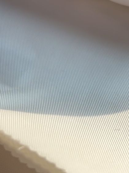 The subtle texture of a white-on-white striped fabric, adding a touch of visual interest to a classic white shirt.