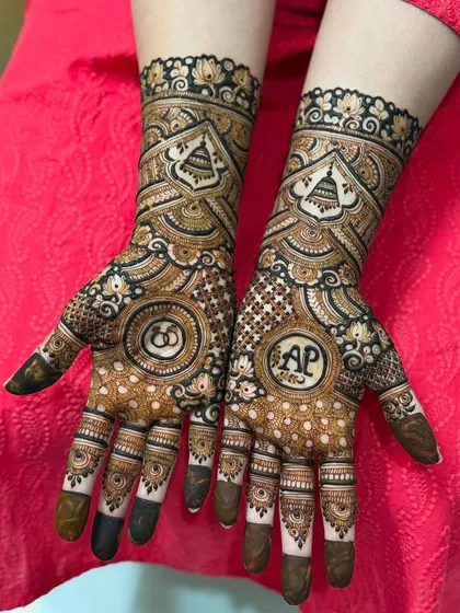 The rich, dark stain of a personalized engagement mehendi, highlighting the couple's initials 'AP' and intertwined rings.