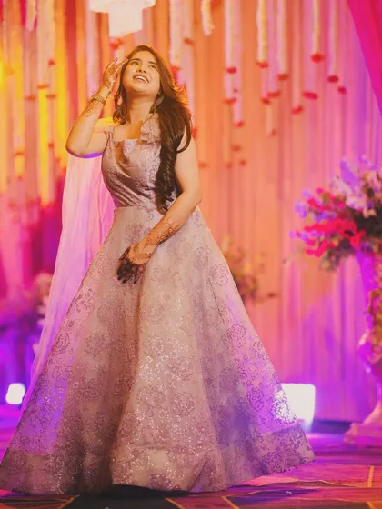 A candid, joyful shot of a client wearing a light purple gown at a wedding event. The dress has a subtle shimmer and a flowing silhouette, perfect for dancing the night away.
