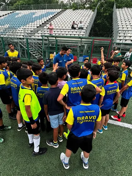 A large group of young players gathers around their coaches and sports psychology experts for a final huddle. This signifies the team-wide importance of mental preparation.