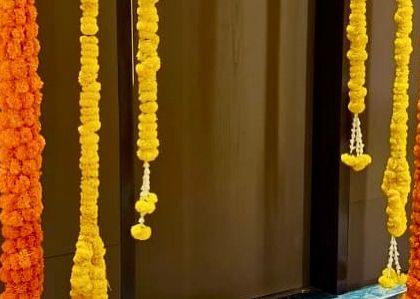 A close-up of our marigold decorations. We use strings of fresh yellow and orange marigolds, sometimes with small white flower accents, to create beautiful hanging decor for doorways, backdrops, and walls.