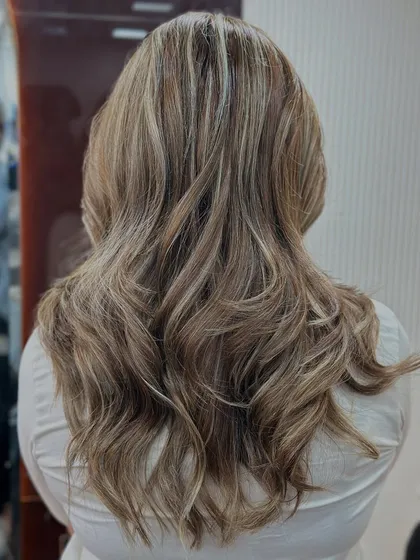 An ash blonde hair color transformation that looks cool and sophisticated. We styled it with waves to show how the light catches the different ashy tones.