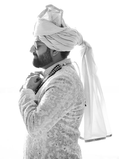 A classic black and white portrait of the groom, capturing the details of his turban and sherwani.