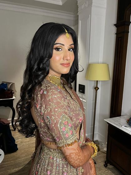 The bride looks gorgeous with her Sangeet hairstyle, featuring deep, glamorous waves and a side part.