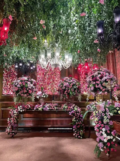A detailed view of a floral-adorned bar or buffet table from a regal reception. The ceiling is a dense canopy of greenery and flowers, creating an immersive, enchanted garden experience indoors.
