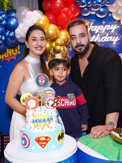 The family gathers for a photo with the birthday boy and his amazing superhero cake. These are the core memories that last a lifetime.