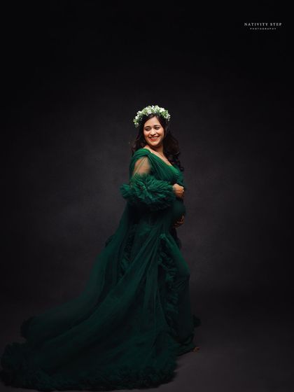 A smiling portrait of the mother-to-be in a green gown and floral crown. Her happy expression is infectious.