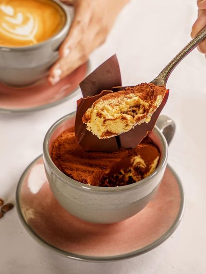 This tiramisu served in a coffee cup is a creative twist on a classic. The photo captures the creamy texture and the dusting of cocoa, creating a cozy and inviting image that pairs perfectly with the idea of a cafe.