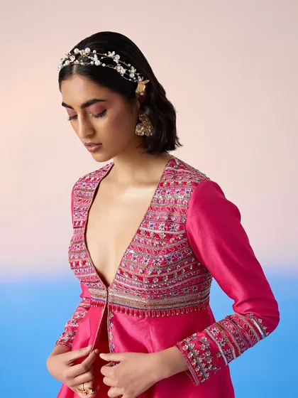 A vibrant pink peplum jacket and sharara set, a fun and festive choice for a sangeet or mehendi.