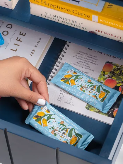 A lifestyle shot for a healthy snack bar, styled as a go-to item in a work drawer. This "in-context" styling makes the product relatable and suggests it as a convenient and smart choice for a busy day.
