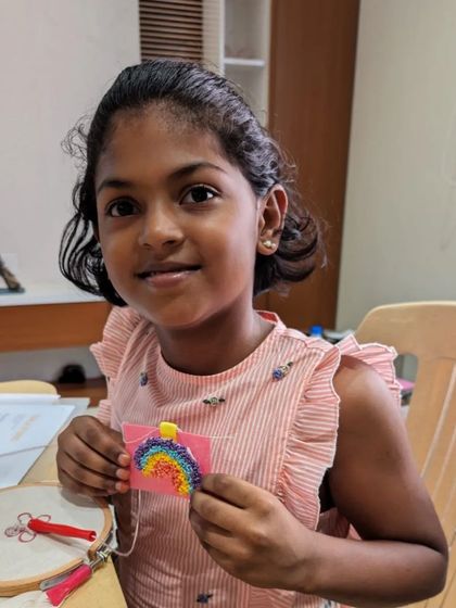 A young girl proudly displays the rainbow charm she made all by herself.