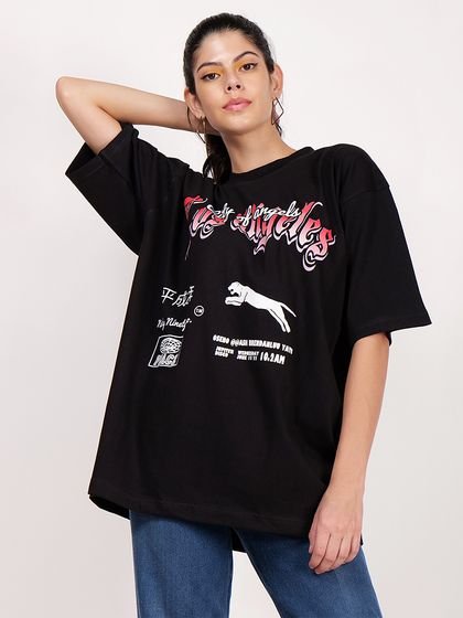 A standing, relaxed pose that clearly shows the oversized fit and full graphic of the black t-shirt.