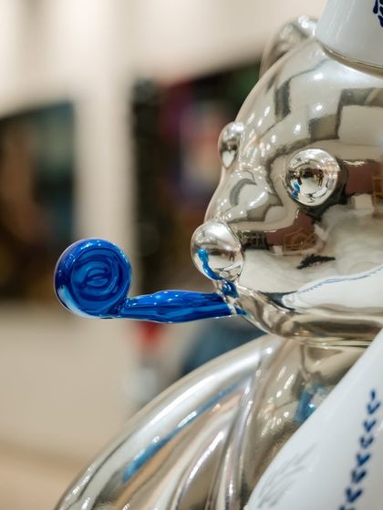 Detail of the silver "Let's Party Teddy," focusing on the blue party blower, adding a pop of color and festive energy.