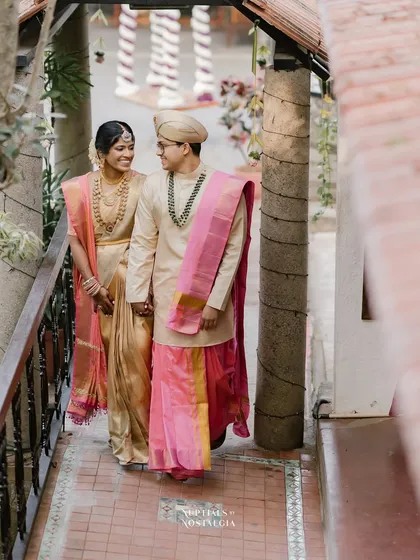 A couple walks along a covered walkway, the repeating pillars and tiled floor creating a lovely sense of perspective.
